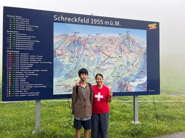 Two people standing in front of a map sign.