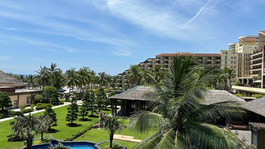 Resort with palm trees and buildings by the sea.