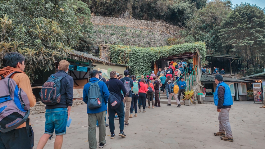       People waiting in line at the entrance of a historical site.
  