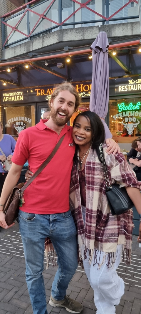 Two people posing outside a restaurant with a blurred background.