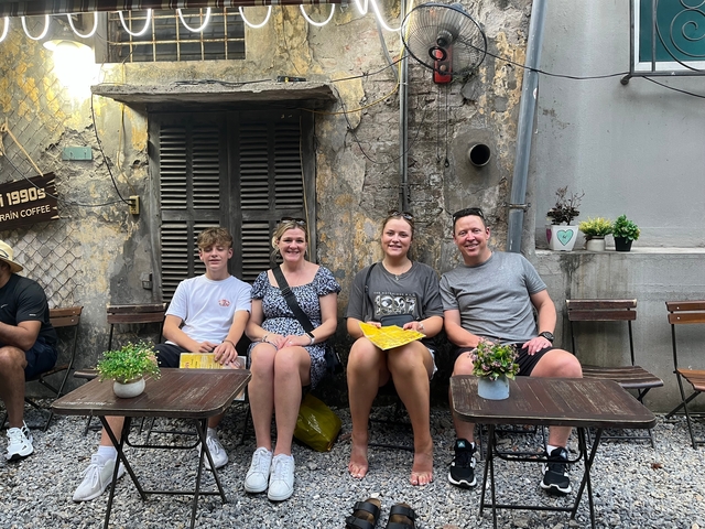 Family sitting at an outdoor cafe with a rustic urban background.