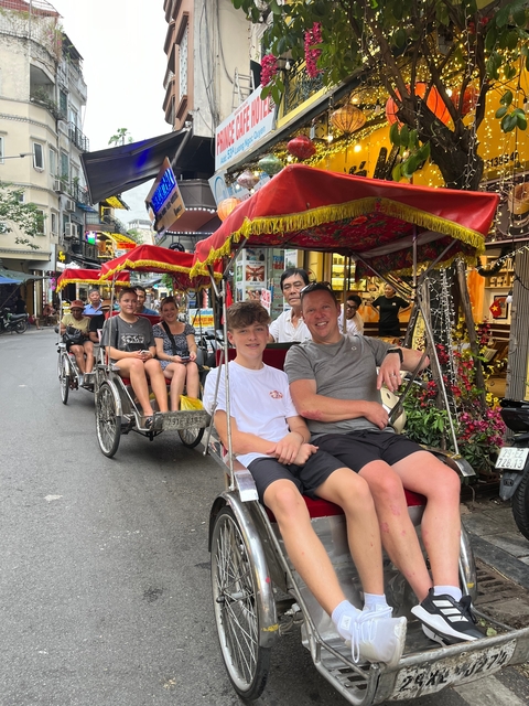 People enjoying a rickshaw ride through a busy street.