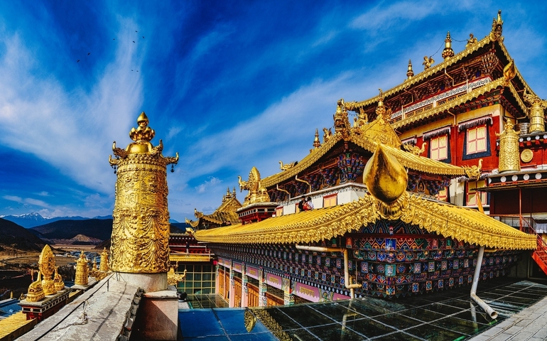 Ornate golden roof of a monastery with blue sky.