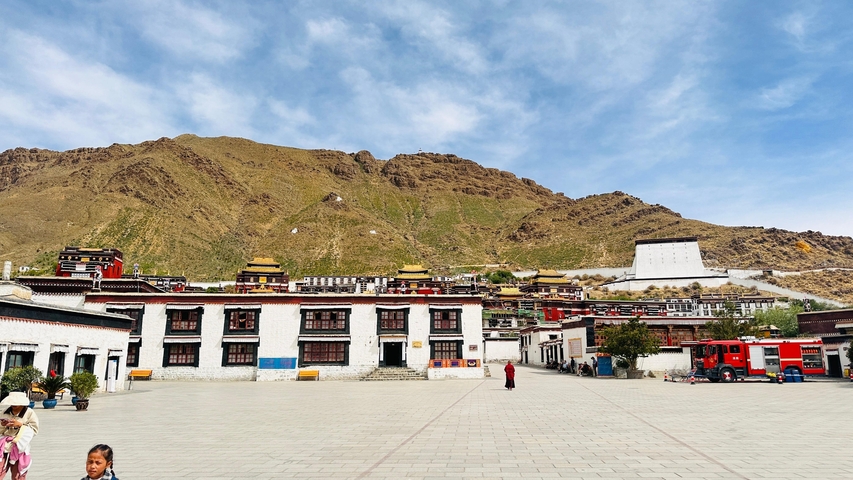Open square with traditional buildings and a mountain backdrop.