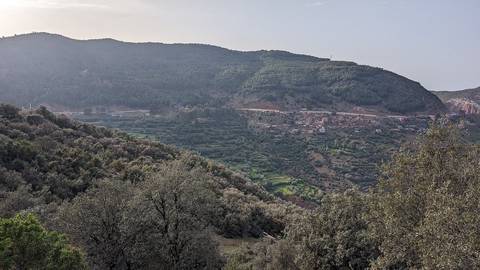 Lush green hills with a distant view of a village.