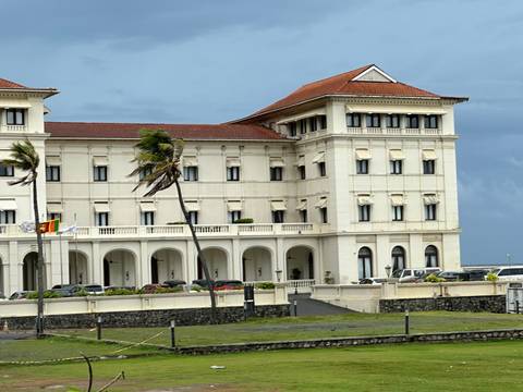 Colonial style building with flags and vehicles.
