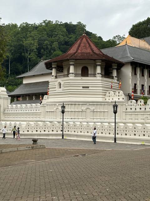       White temple-like building with tourists in the foreground.
  
