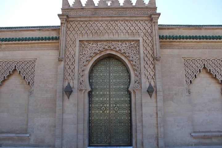 Large ornate door with intricate patterns in a stone wall.