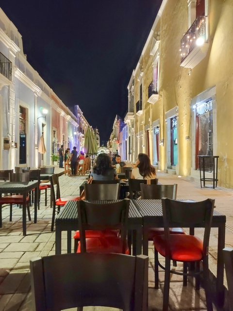       Nighttime street cafe with people dining outdoors.
  