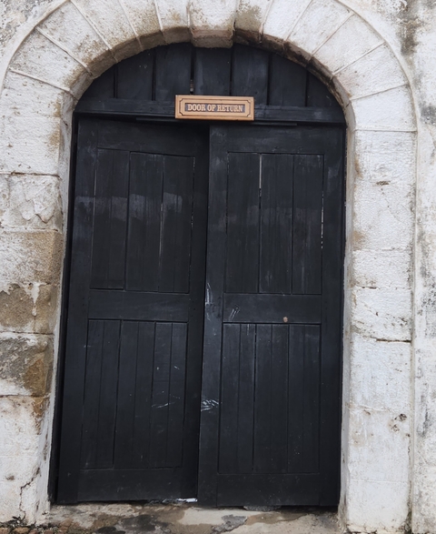       Closed black wooden doors set in a stone wall.
  