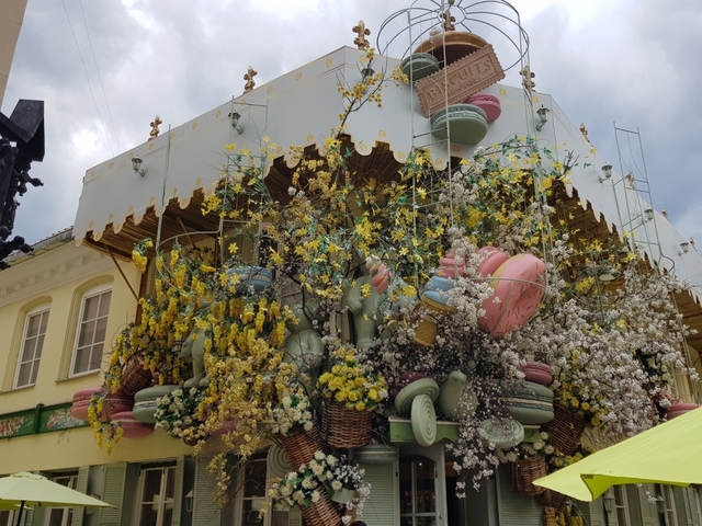       Building facade decorated with an abundance of flowers and macarons.
  