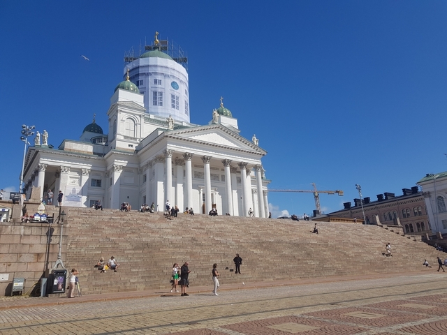       Helsinki Cathedral on a sunny day with people on the stairs.
  