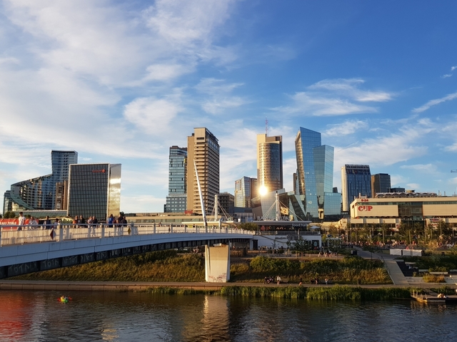       Modern cityscape with a bridge in the foreground and skyscrapers reflecting sunlight.
  