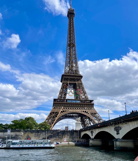 Eiffel Tower with Olympic rings against a blue sky.