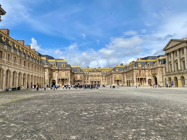 Palace courtyard filled with tourists under a blue sky.