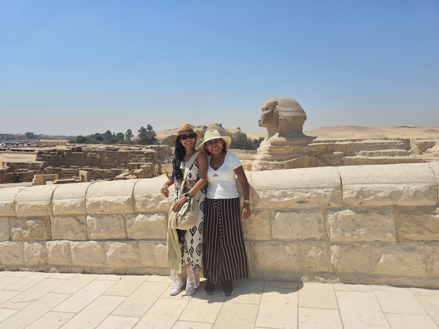       Two people posing in front of the Sphinx and pyramids.
  