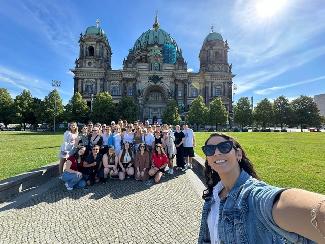 Group of people posing in front of a grand historic building.