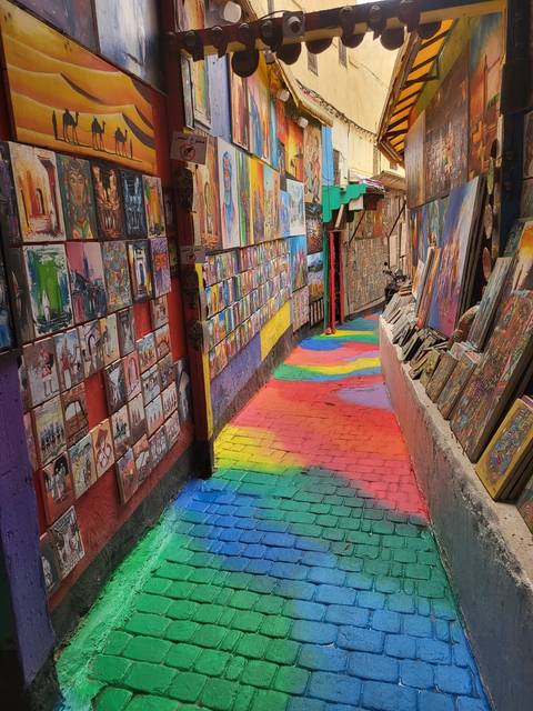 A colorful alley lined with vibrant paintings and artworks.