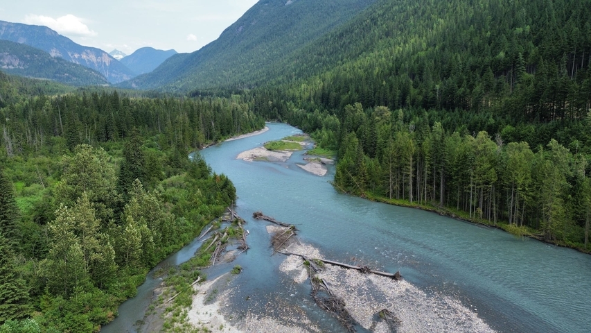       A winding river through a lush green forested valley.
  