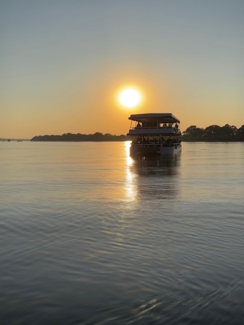 A boat on a river at sunset reflecting in the water.
