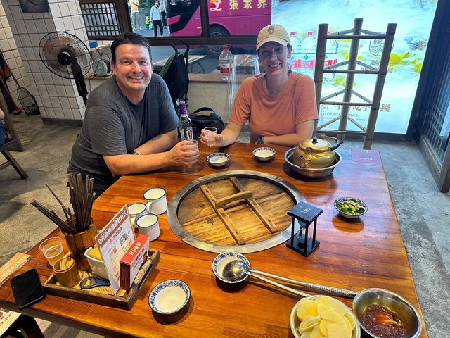       Couple dining at a traditional Chinese restaurant with a hot pot centerpiece.
  