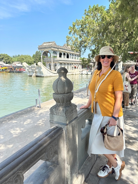       Person posing by a riverside with traditional Chinese architecture.
  