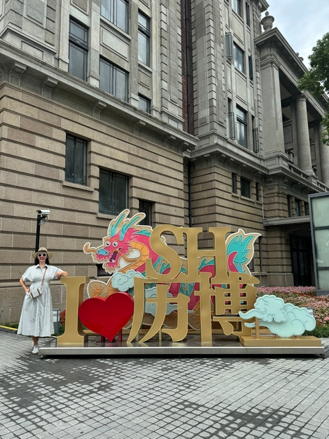 A person posing with a colorful dragon sculpture in front of a building.
