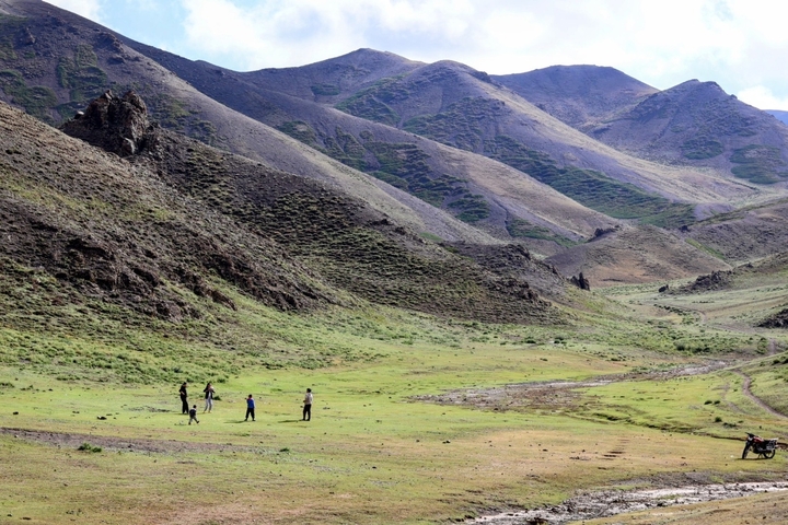 Valley with green grass surrounded by rocky hills.