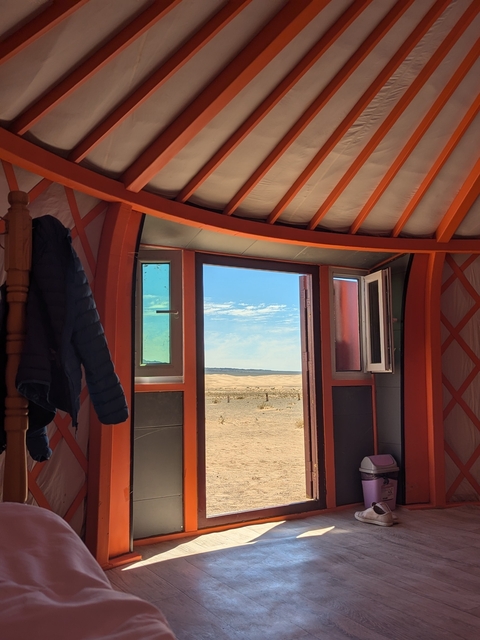 View through a yurt door showing desert and blue sky.