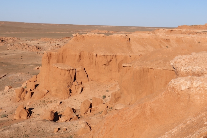       Rock formations in a desert landscape with blue sky.
  