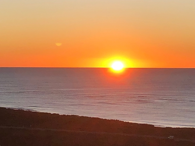 Sunset over the ocean with a clear sky.