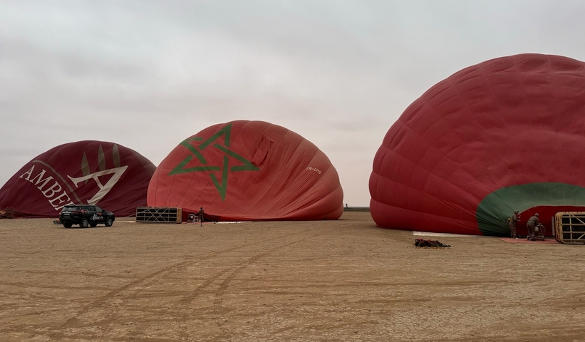       Hot air balloons deflated on the desert ground.
  