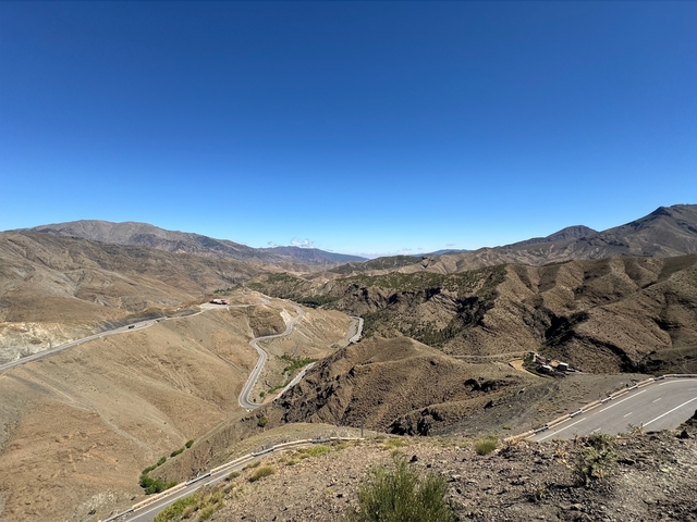       Panoramic view of desert mountains with winding road.
  