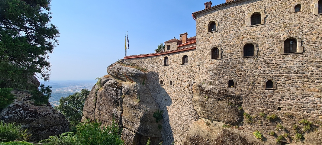       Stone monastery on cliff with flags
  