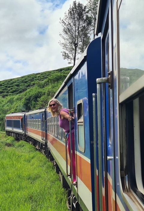 Woman leaning out of a colorful train window.