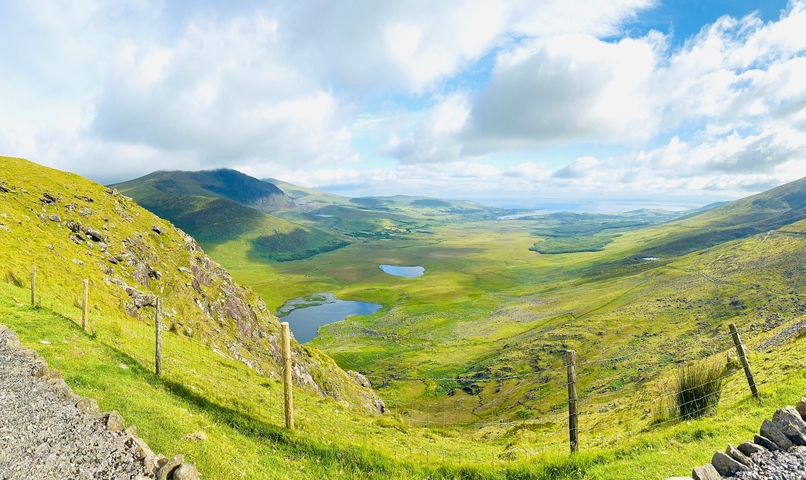       Panoramic view of lush green valley with mountains in distance.
  