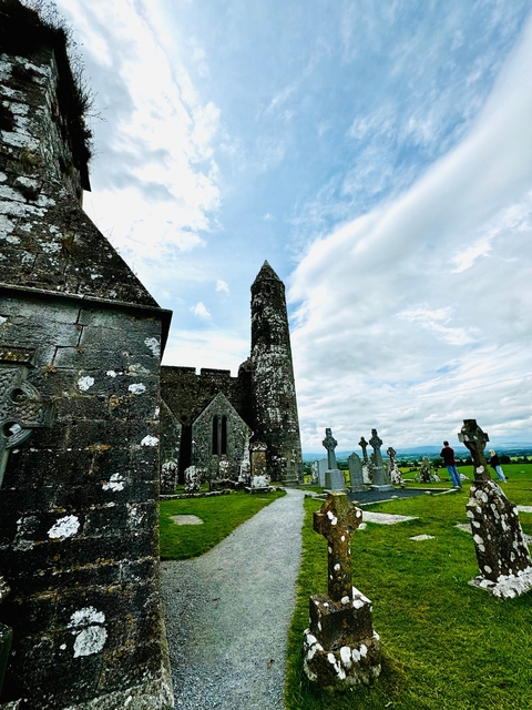       Historic church with cemetery in front and scenic backdrop.
  