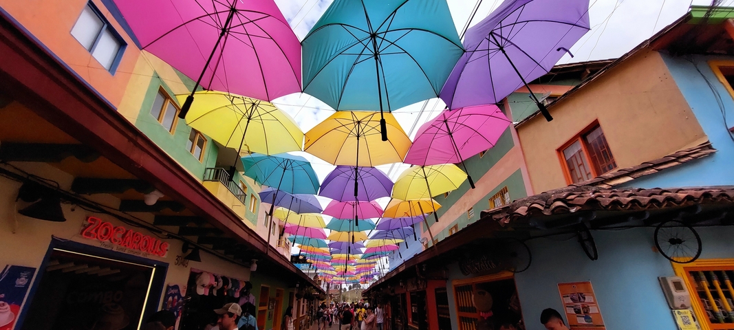Street with colorful umbrellas hanging overhead.