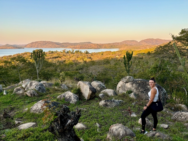       Woman posing in a rocky landscape with a lake view.
  