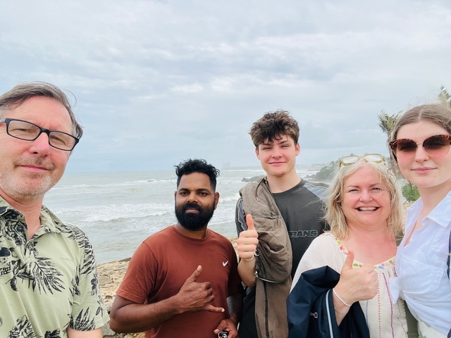 Group of people taking a selfie in front of an ocean backdrop with cloudy skies.
