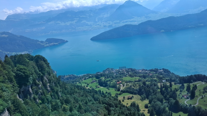 Scenic view of a lake surrounded by mountains and forests from above.