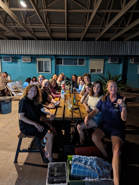       Group of people socializing at night at a wooden table.
  