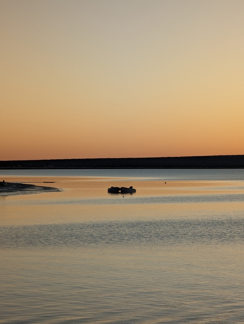       Calm body of water reflecting the sky during sunset.
  