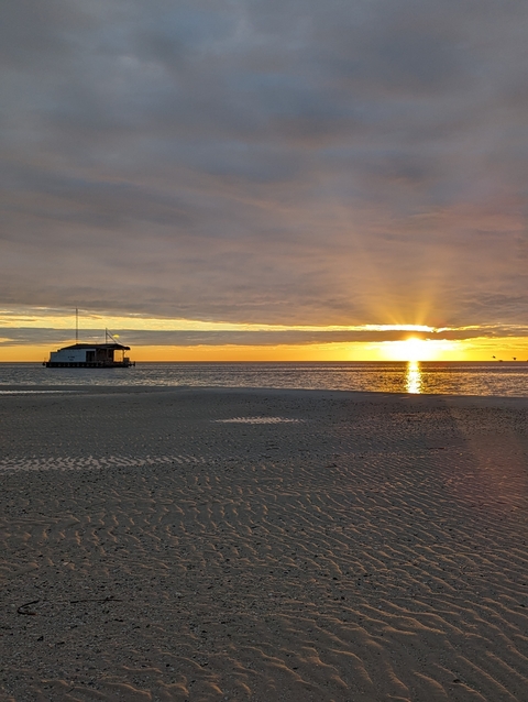       Sun setting over the ocean with a boat in the distance.
  