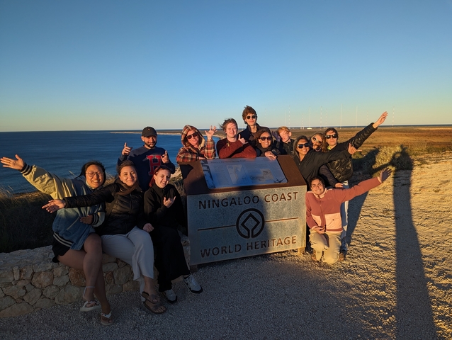       Group of people posing at Ningaloo Coast World Heritage sign.
  