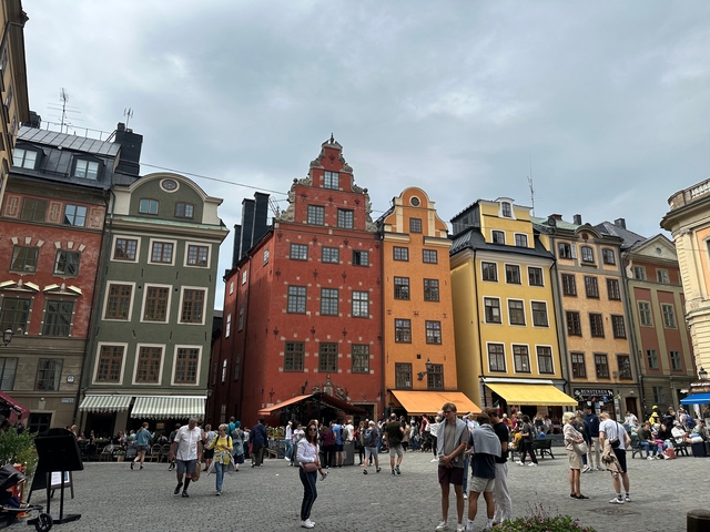 Colorful buildings in a busy city square with people strolling.