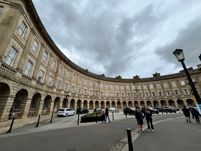       Curved row of historic buildings with people walking.
  