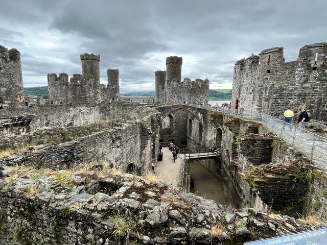 Stone castle with multiple towers and walls, visited by tourists.