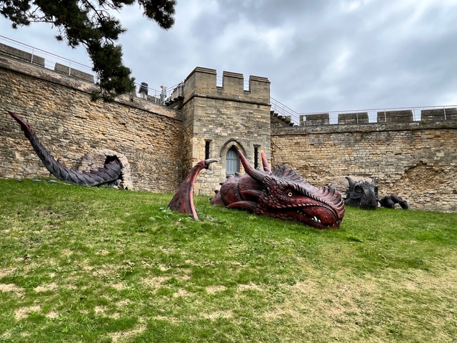 Large dragon sculptures outside a stone fortress.