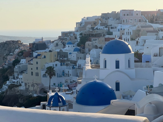 Iconic blue-domed churches in Santorini overlooking the sea.